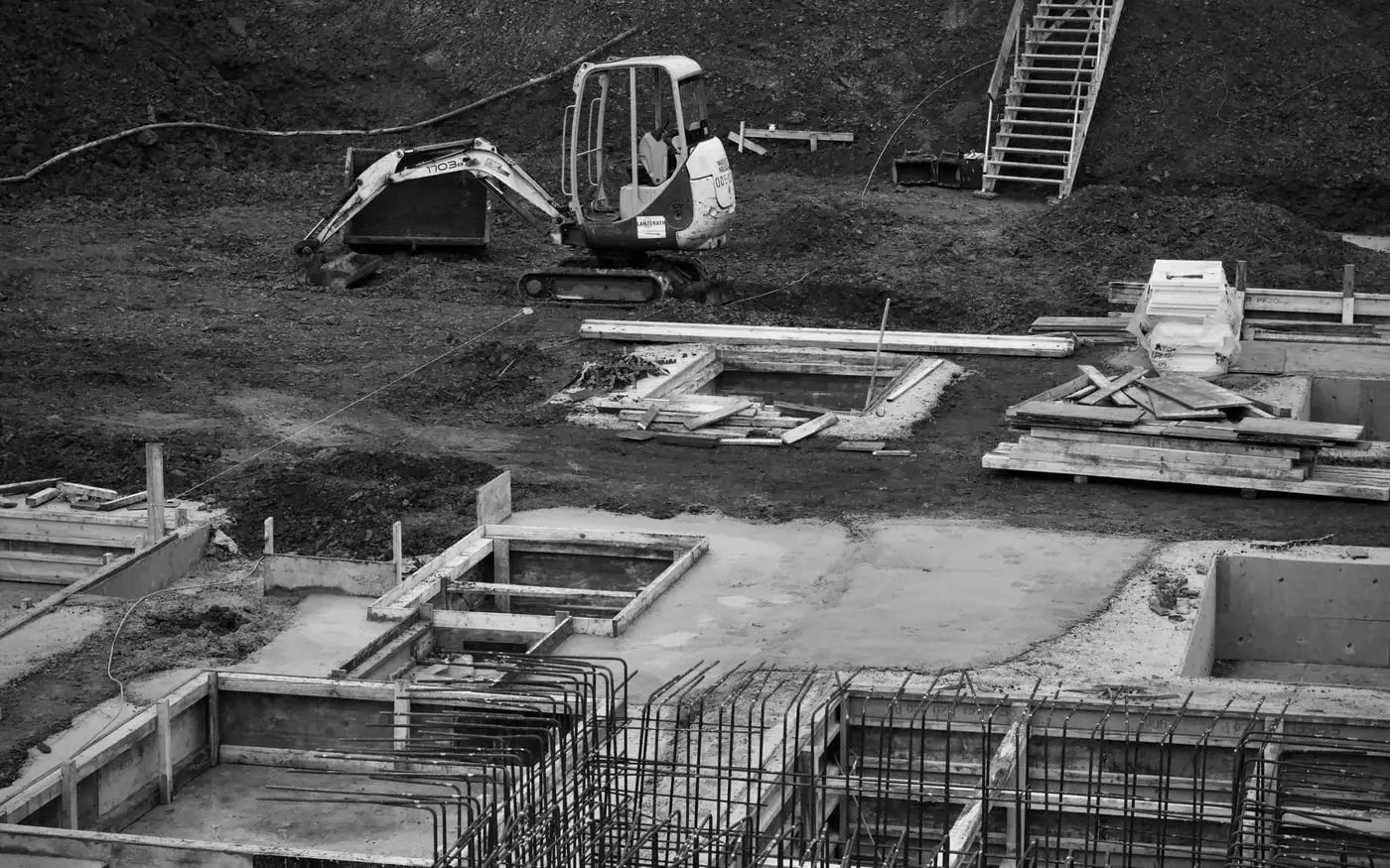Excavadora en una obra con cimentaciones ya ejecutadas, imagen en blanco y negro Excavadora en una obra con cimentaciones ya ejecutadas, imagen en blanco y negro